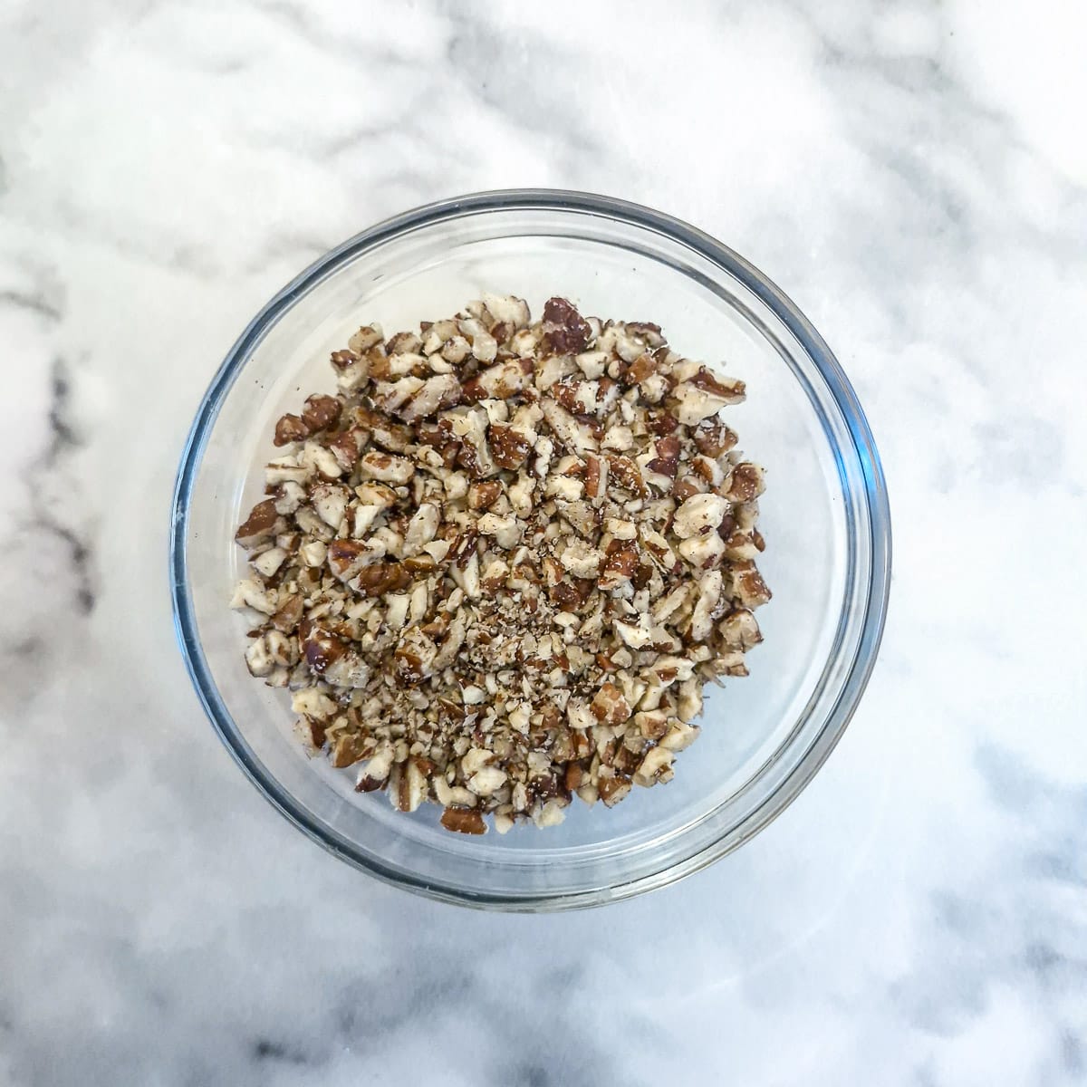 Chopped pecan nuts in a small glass bowl.