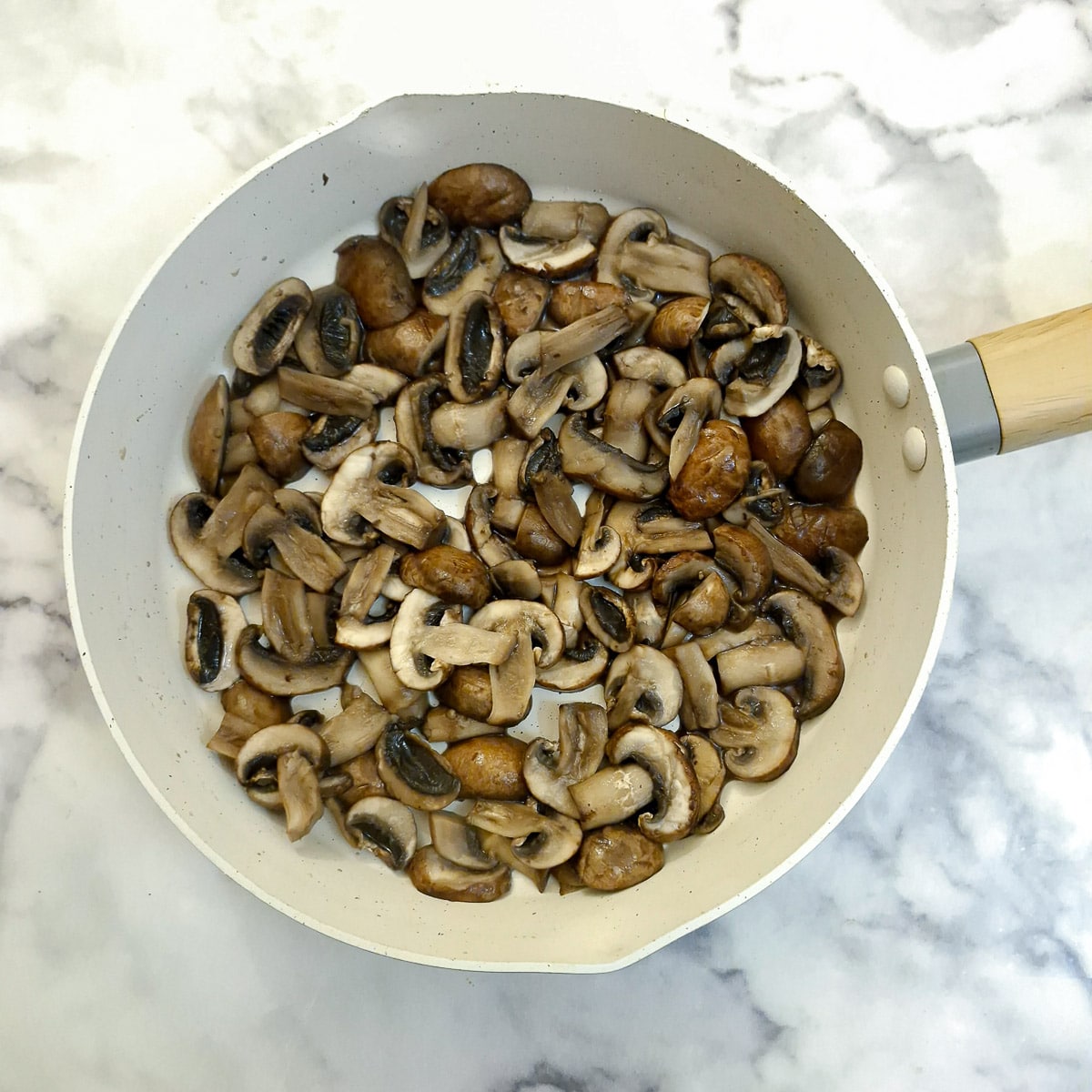 Sliced mushrooms in a frying pan.