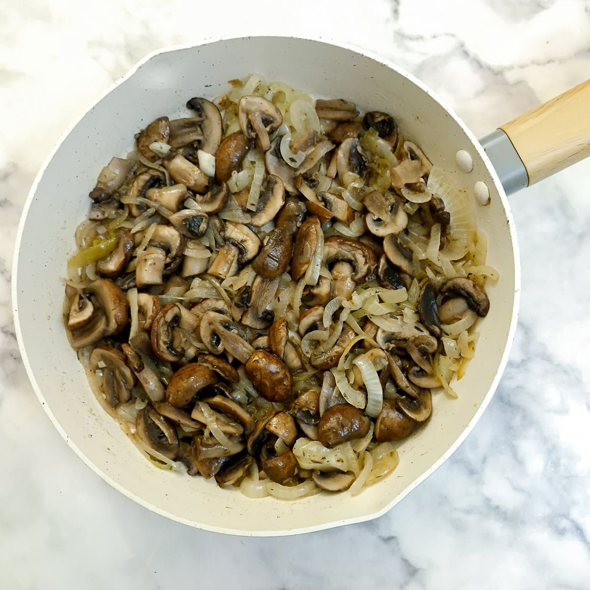 Mushrooms and onions in a frying pan.