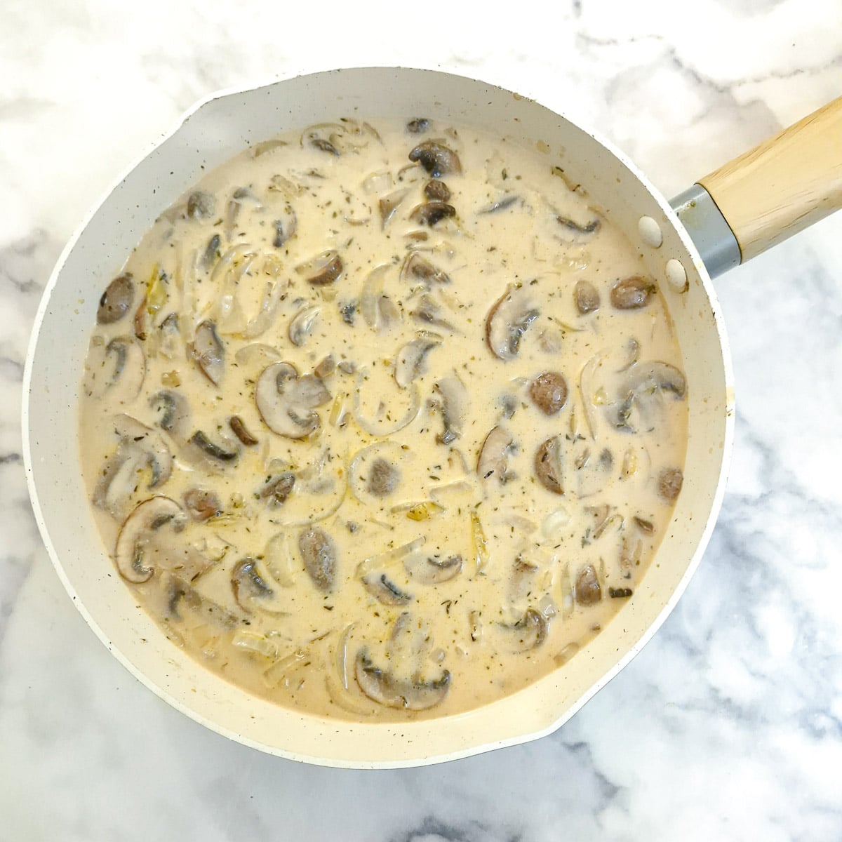 Mushroom sauce in a pan after the addition of stock and cream.