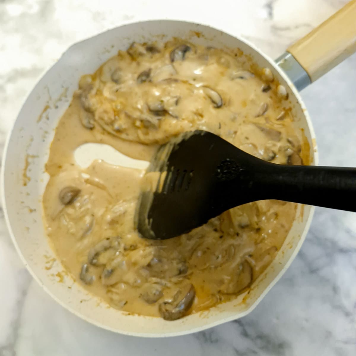 A pan of thickened hunter's sauce with a spoon drawing a trail.