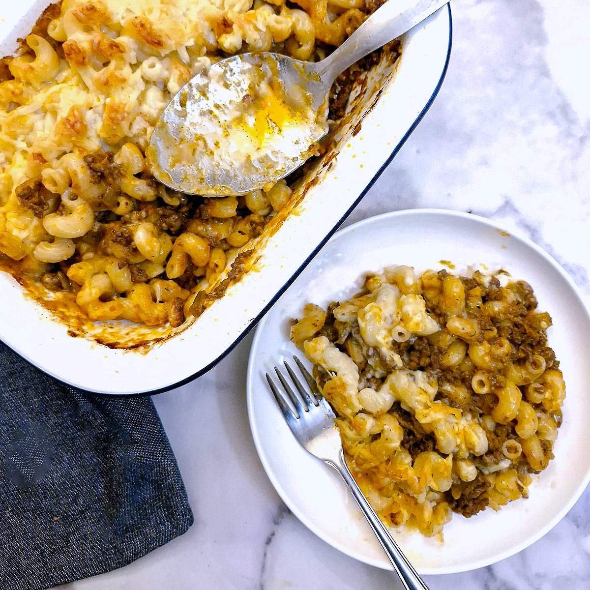 Mac n cheese on a plate next to the serving dish.