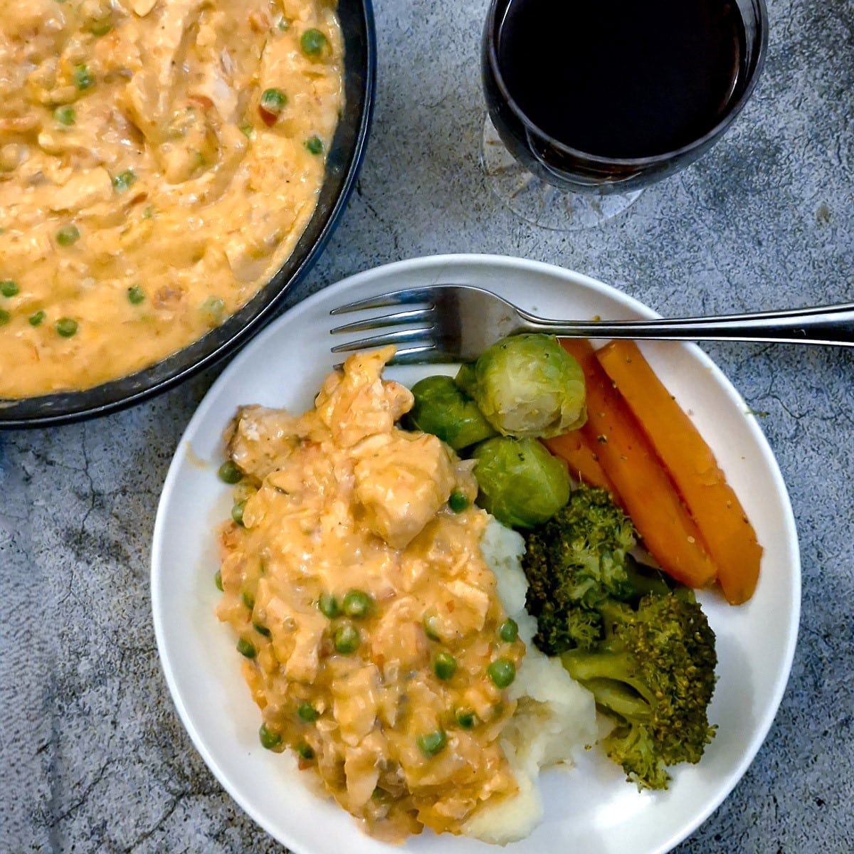 Poached salmon in creamy red pepper sauce on a white plate with vegetables.