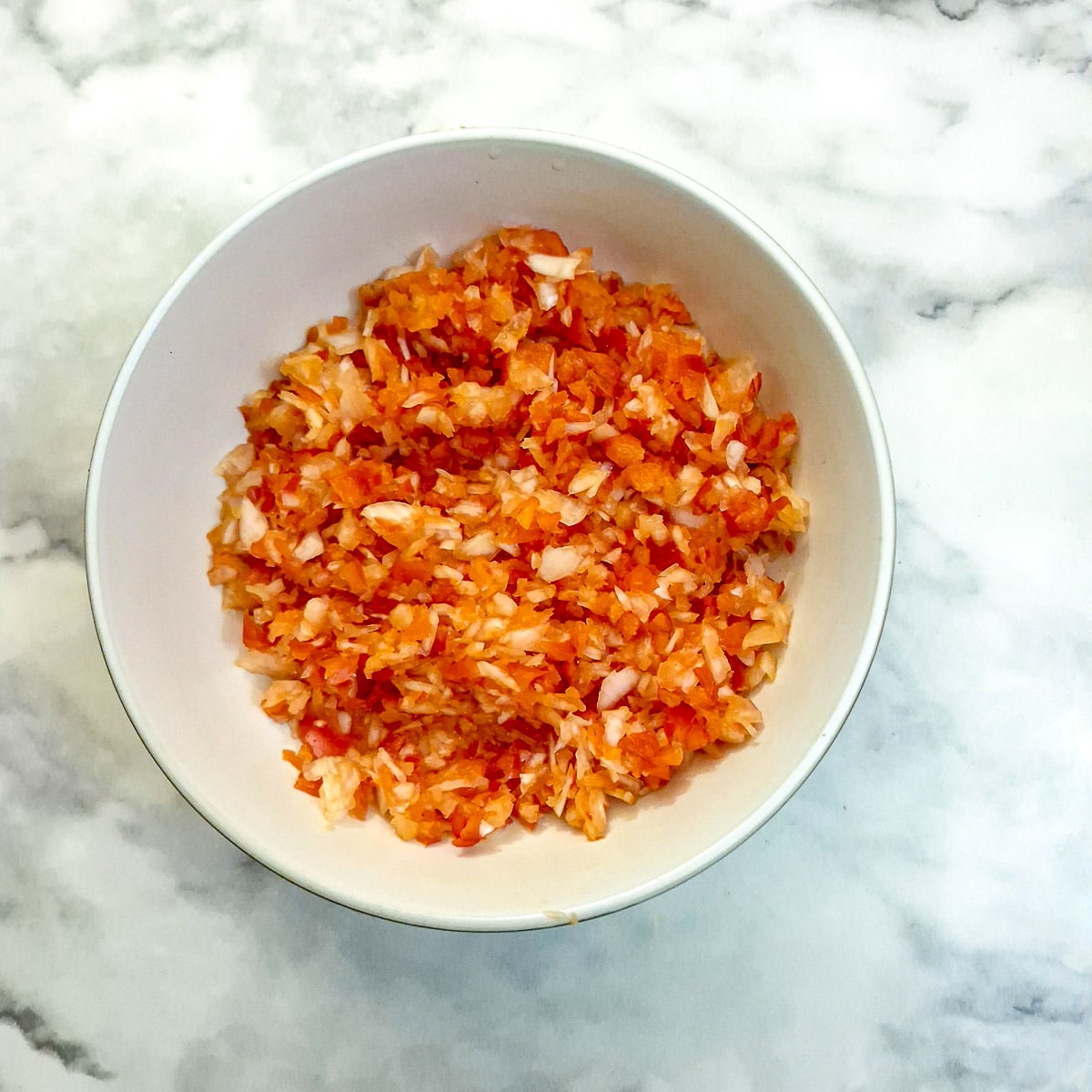 Finely chopped onion and capsicum in a small white bowl.