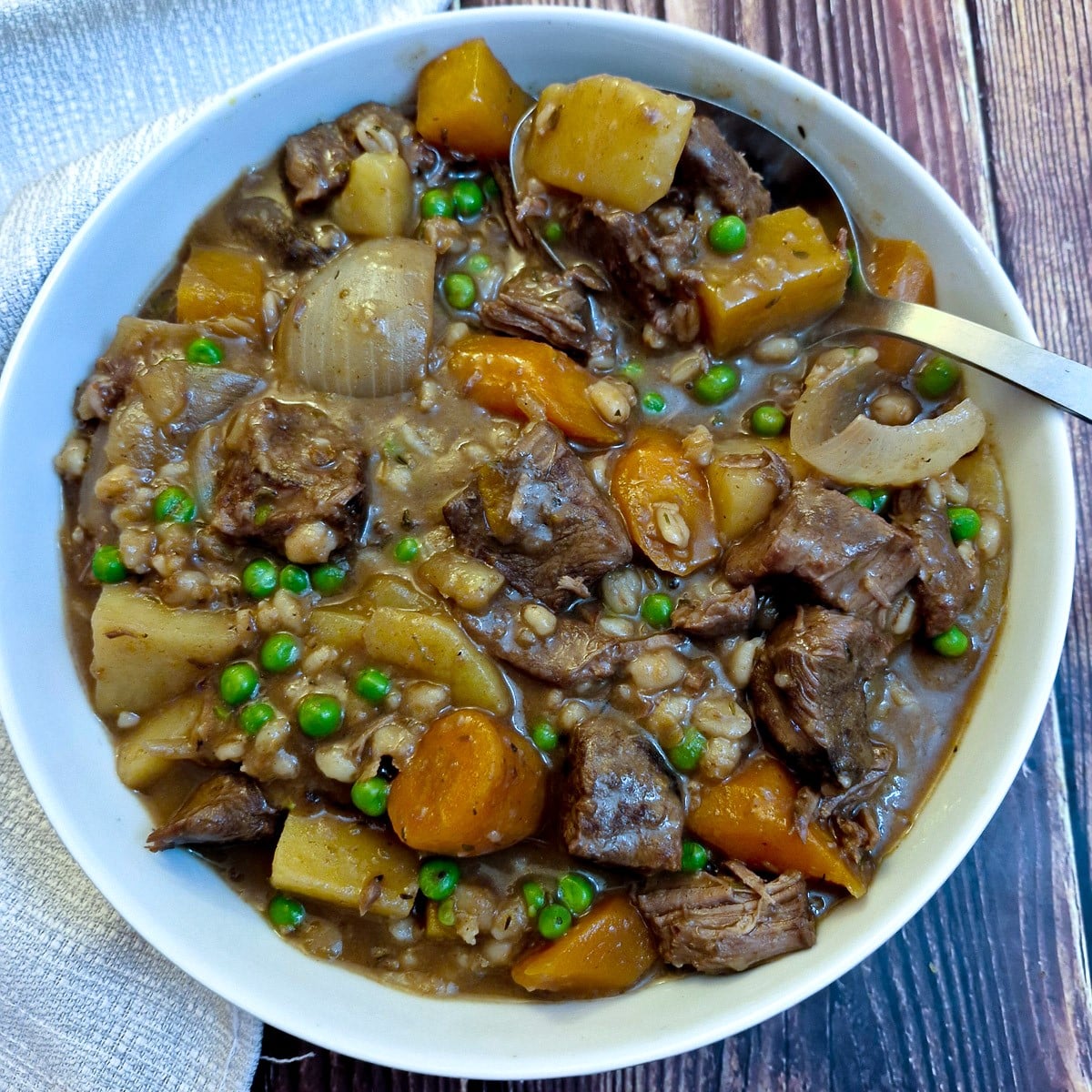 Overhead shot of hearty beef stew in a serving dish with a large spoon.