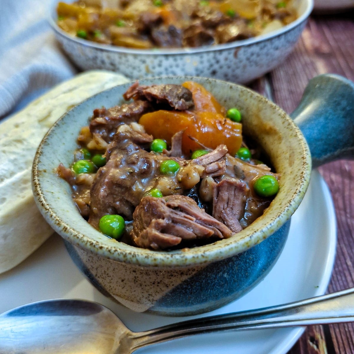 Close up of hearty beef stew in  small dish with a handle.