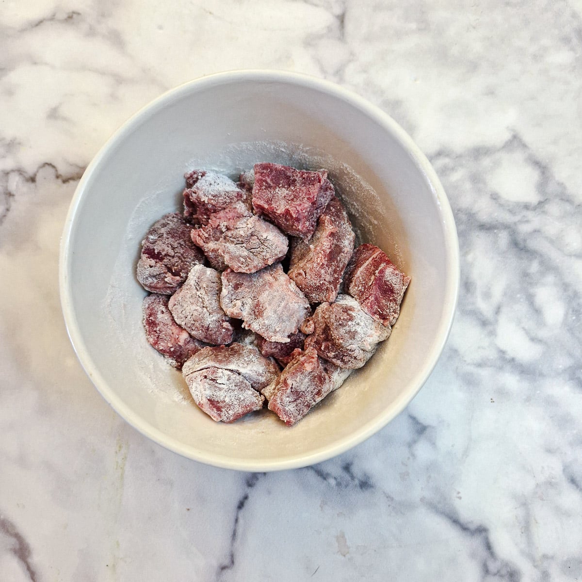 Beef cubes coated in seasoned flour.