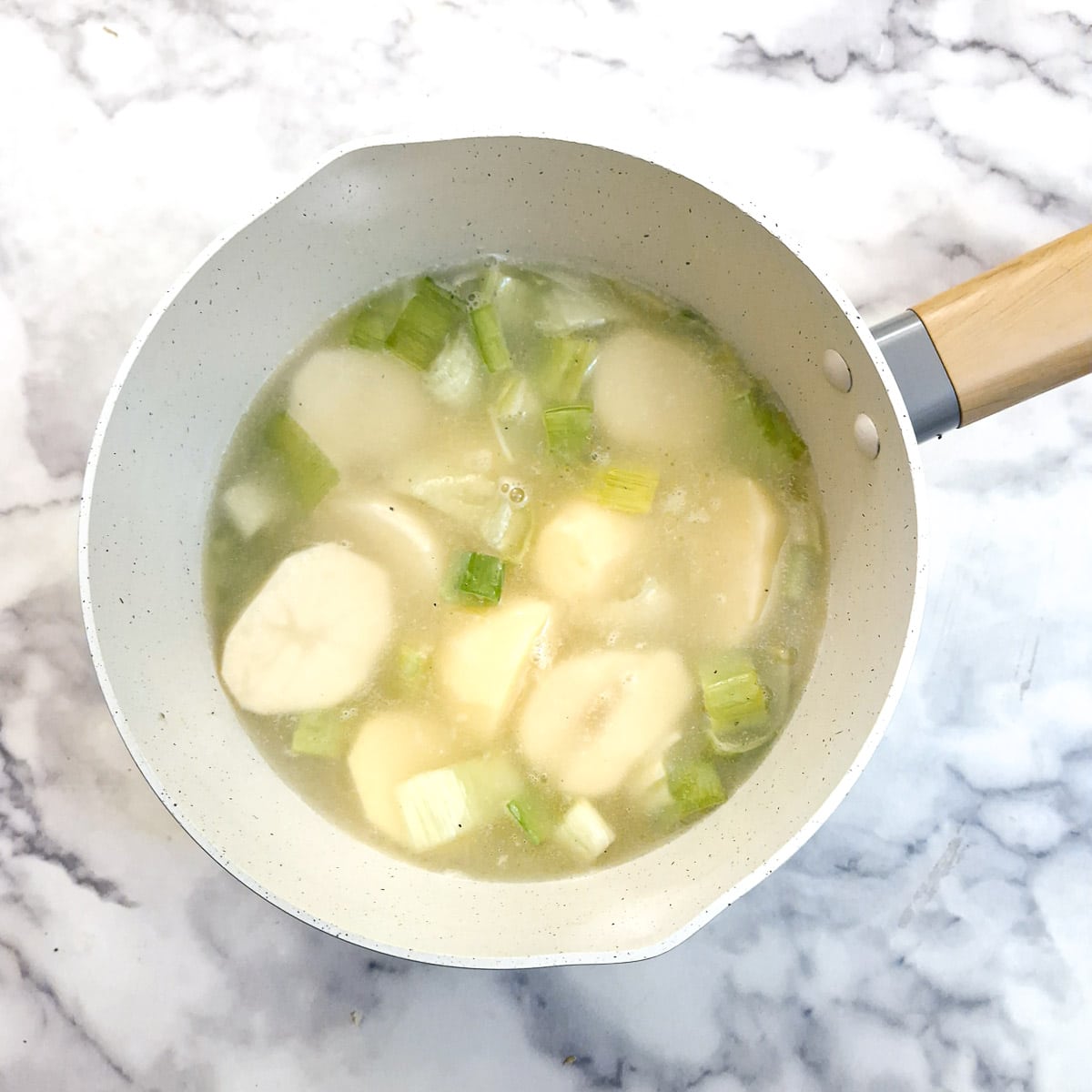 Potatoes and leeks in a saucepan with water.