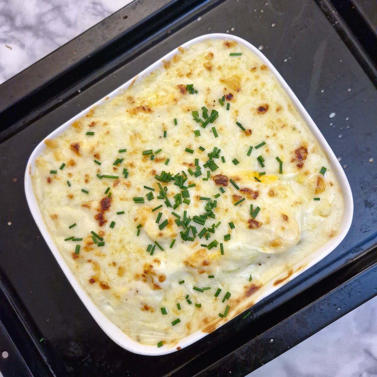 A baked dish of Anglesey eggs garnished with chopped chives.