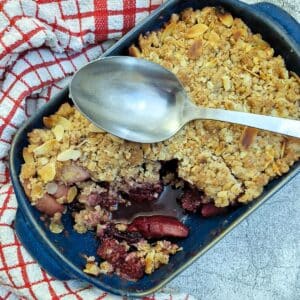 Overhead shot of apple and blackberry crumble with one corner removed.