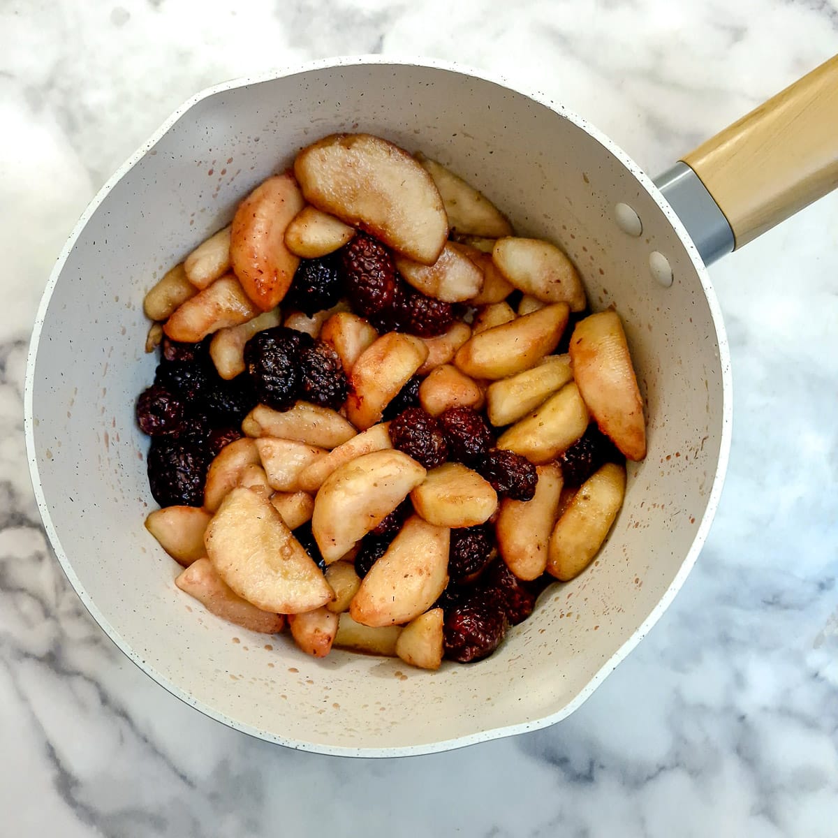 Apples and blackberries in a saucepan.