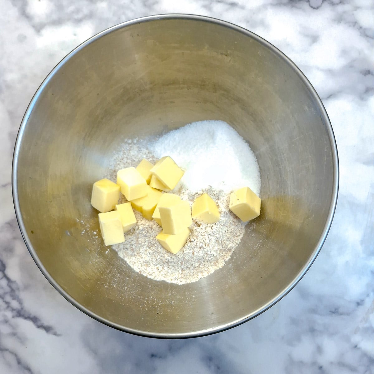 Flour butter and sugar in a metal mixing bowl.