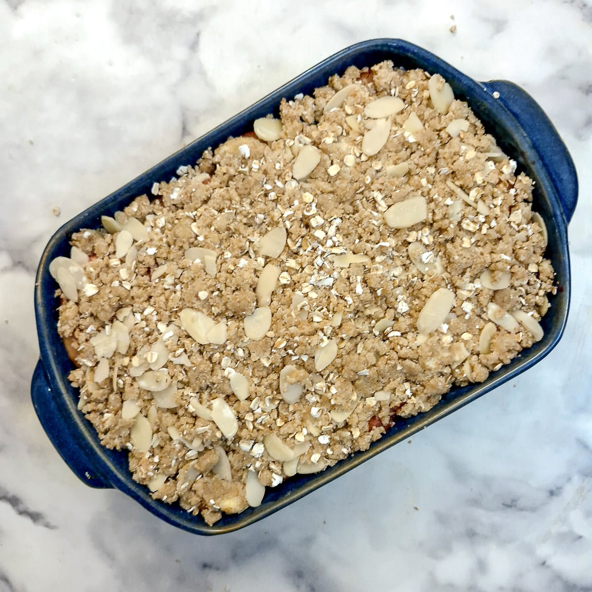 A fully assembled unbaked blackberry and apple crumble.