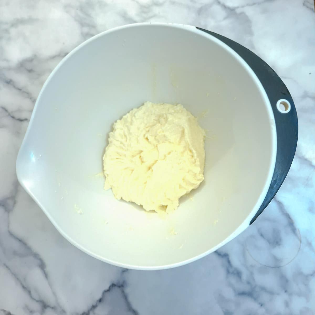 Butter and sugar combined with eggs in a mixing bowl.