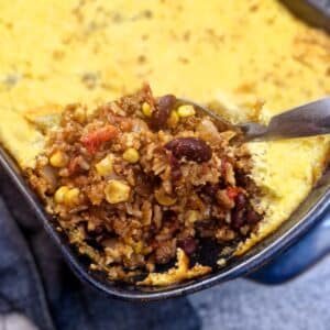A spoon ful of chilli con carne corn casserole being lifted from a dish.