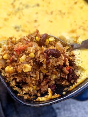 A spoon ful of chilli con carne corn casserole being lifted from a dish.