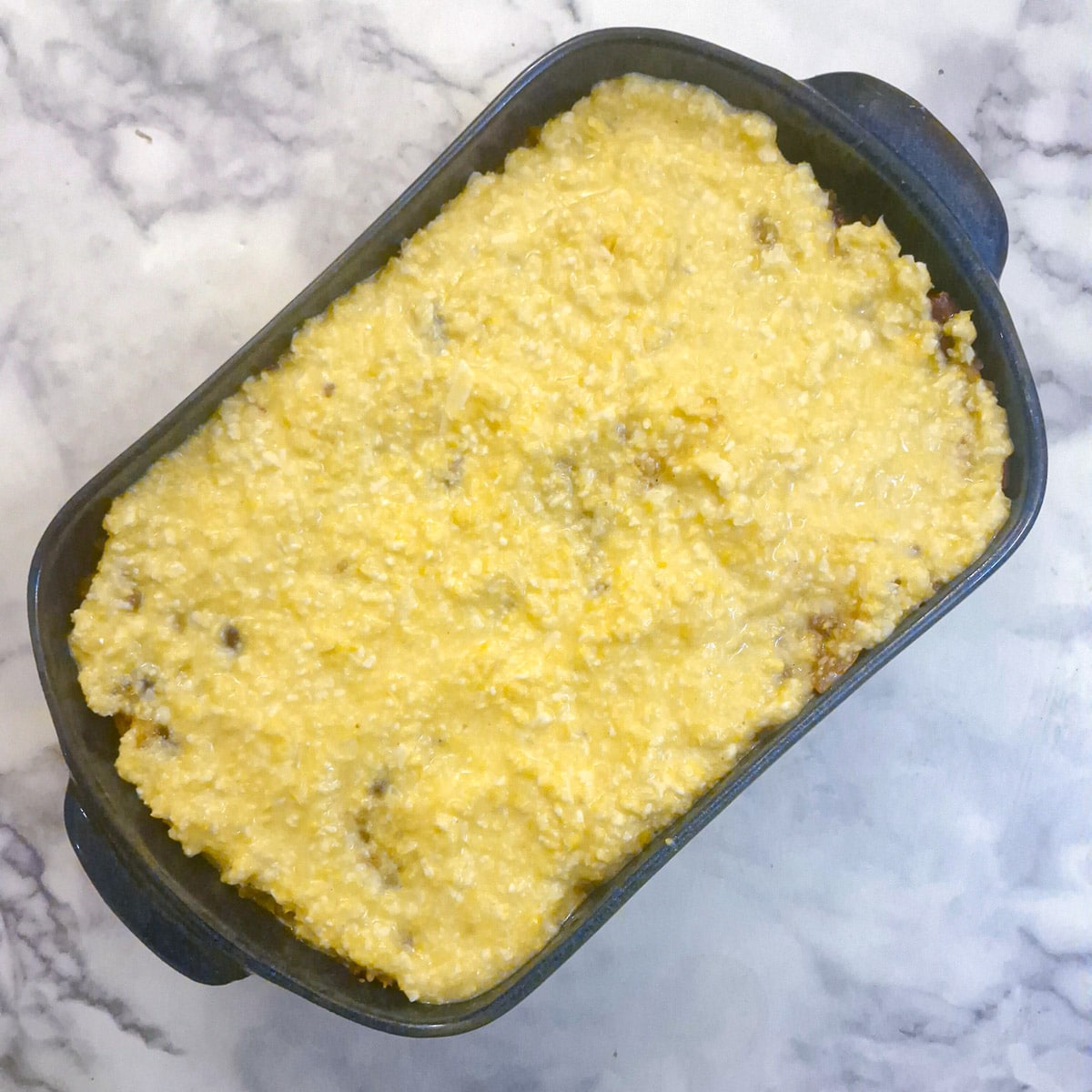 Corn topping spread over chilli mince in a casserole dish.