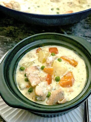A dark green soup bowl filled with creamy salmon chowder.