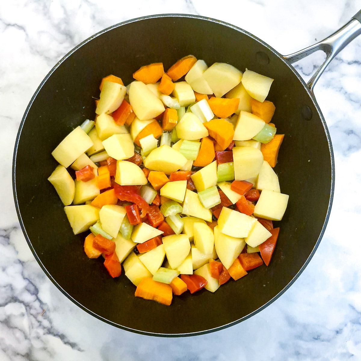 Chopped potatoes, carrots, red pepper and celery in a large saute pan.