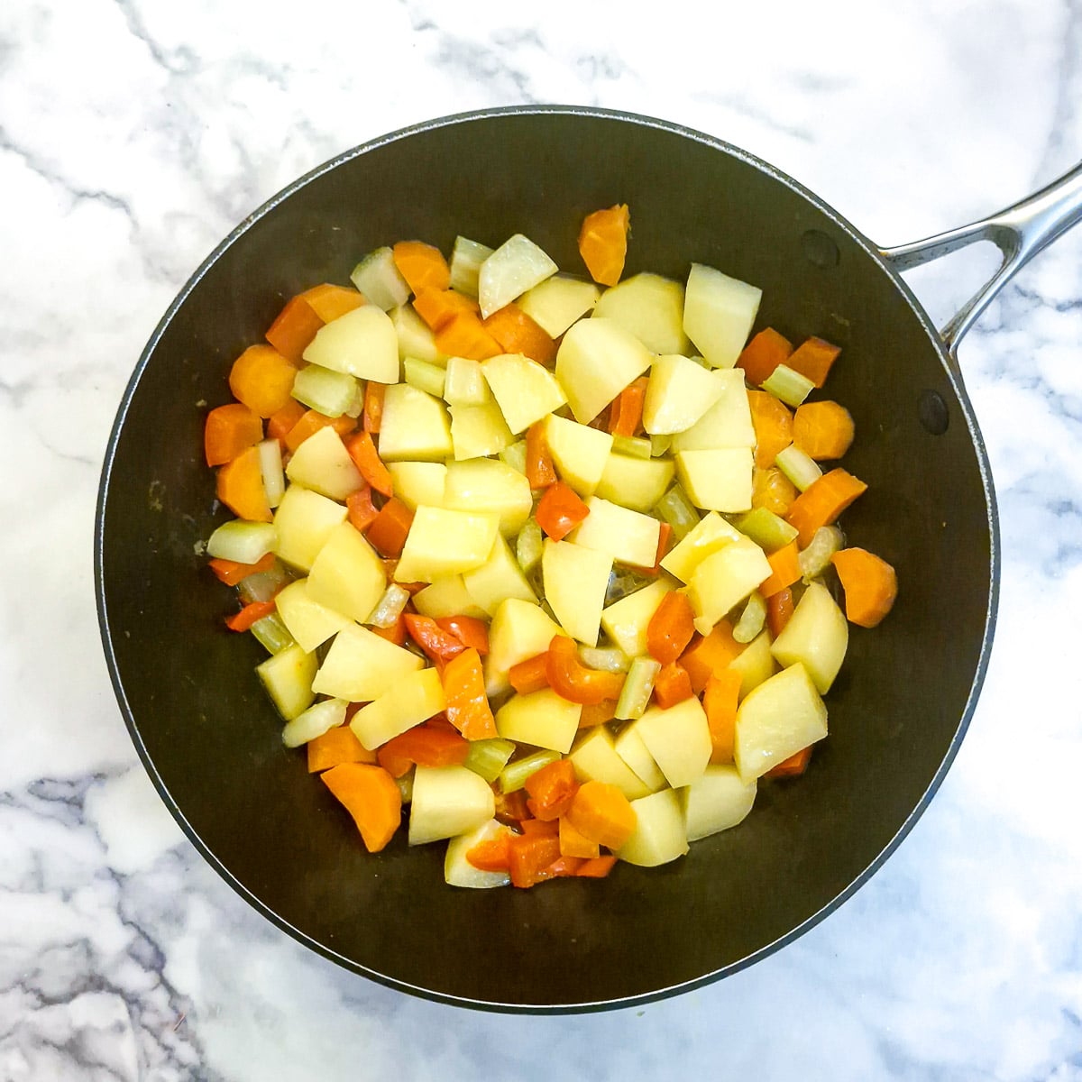 Partly softened vegetables in a saute pan.