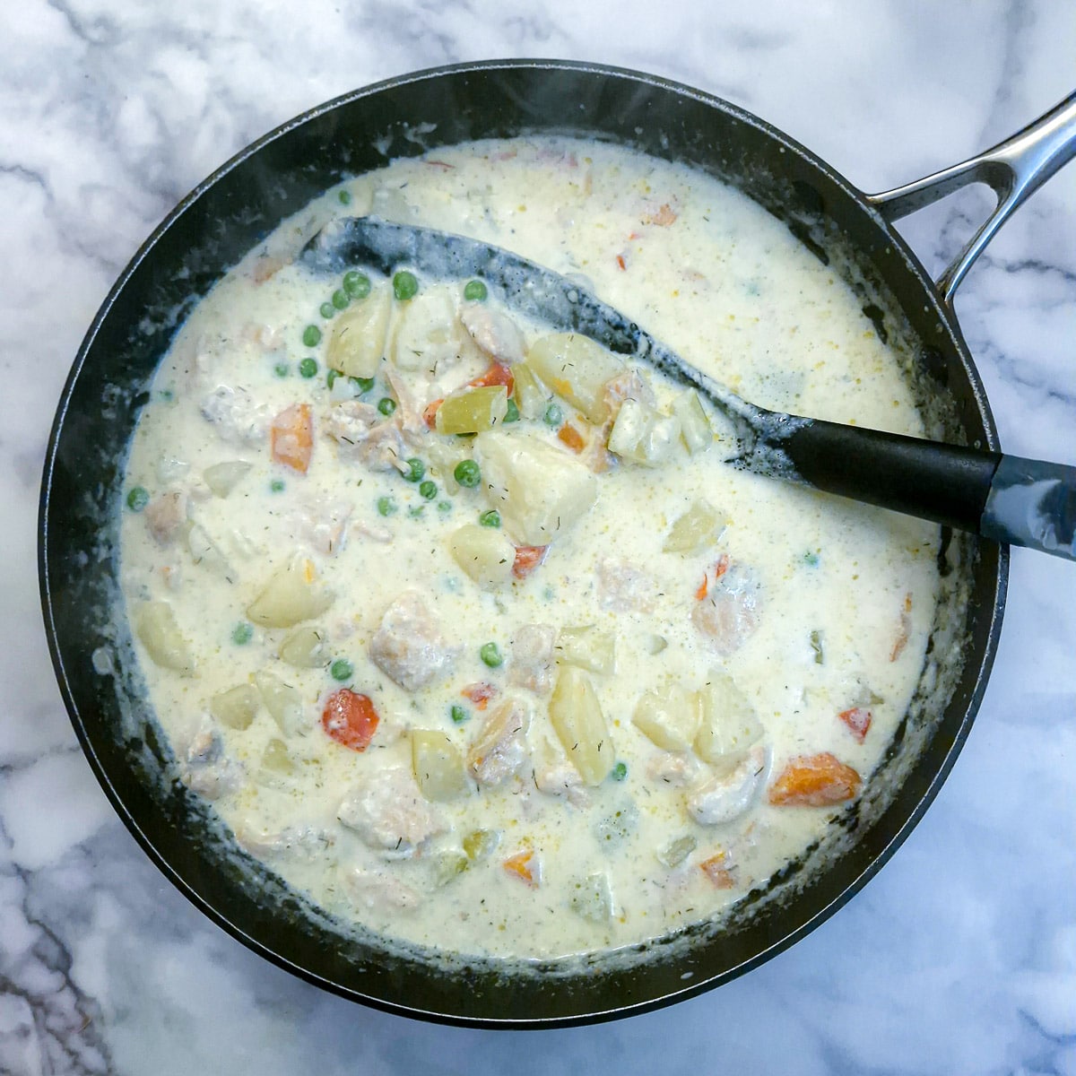 A saute pan filled with thickened salmon chowder.