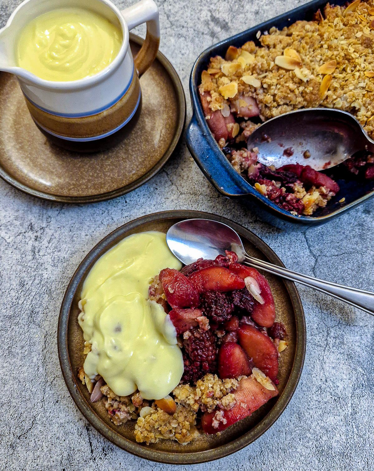 Vanilla custard poured over a serving of blackberry and apple crumble.