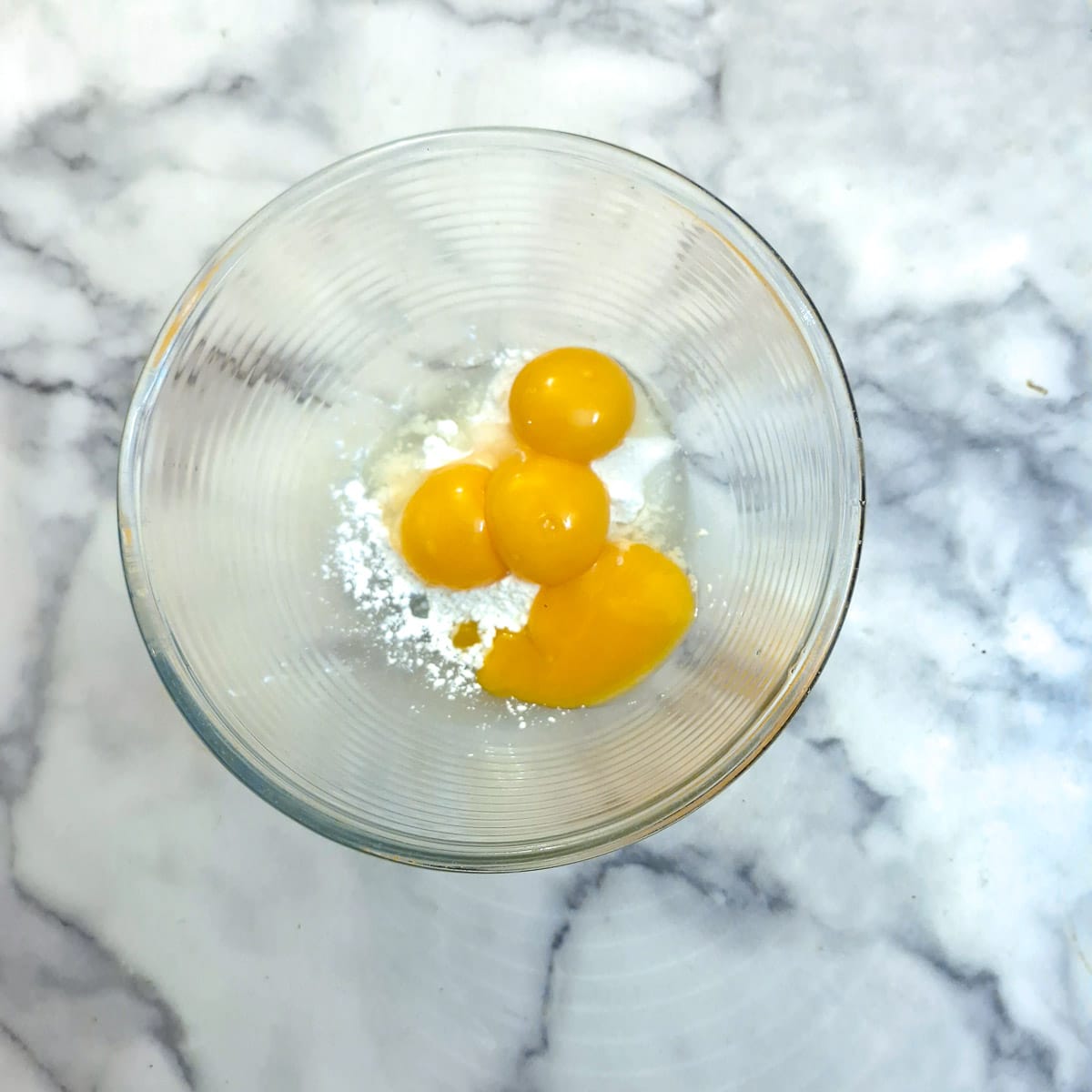 4 egg yolks with cornflour in a glass bowl.