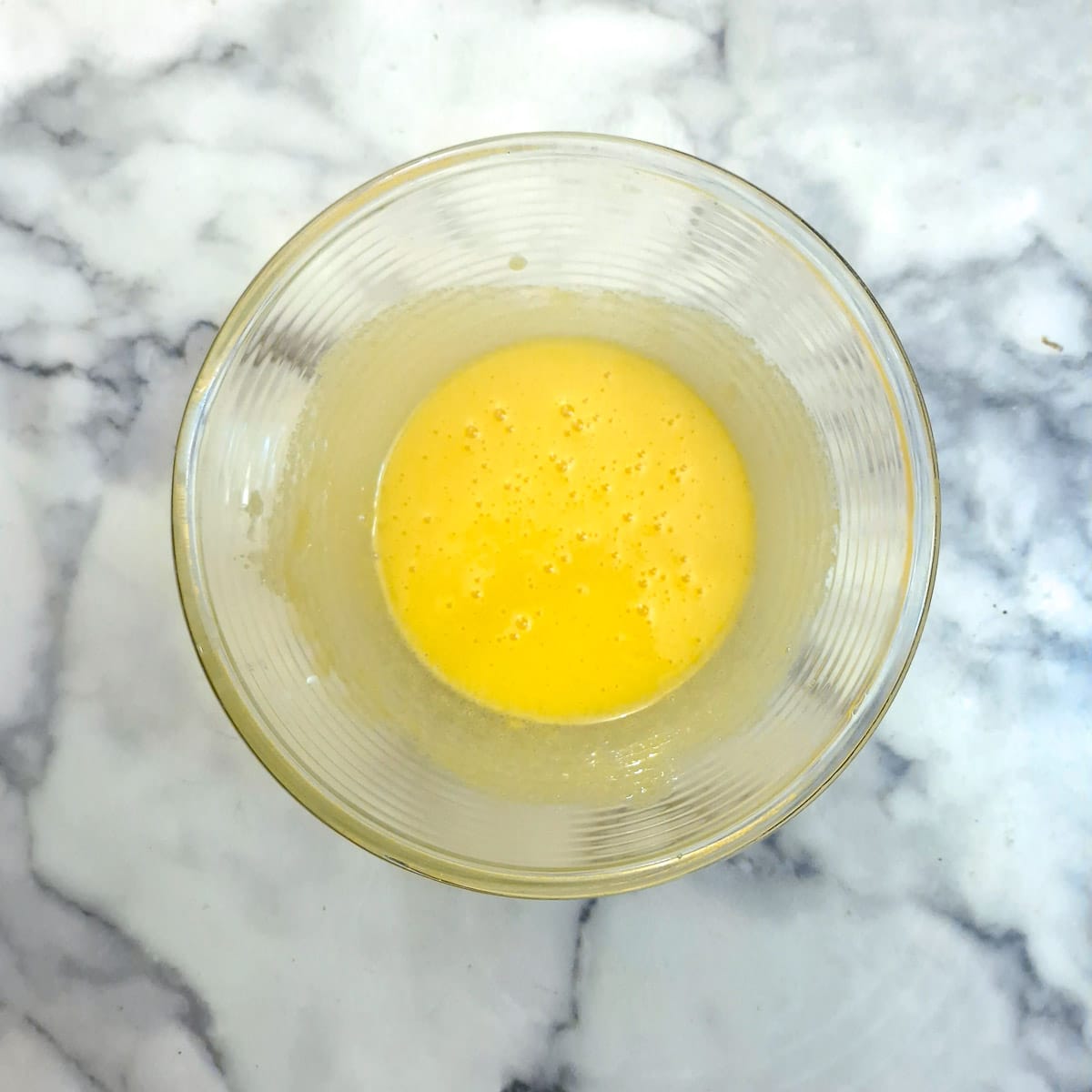 Eggs and cornflour whisked together in a glass bowl.