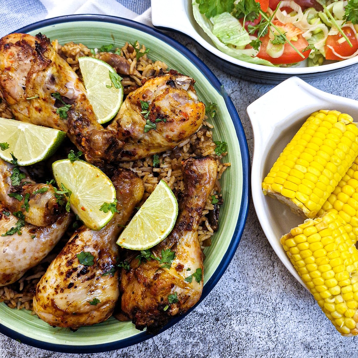 A dish of chicken drumsticks garnished with parsley and wedges of lime.