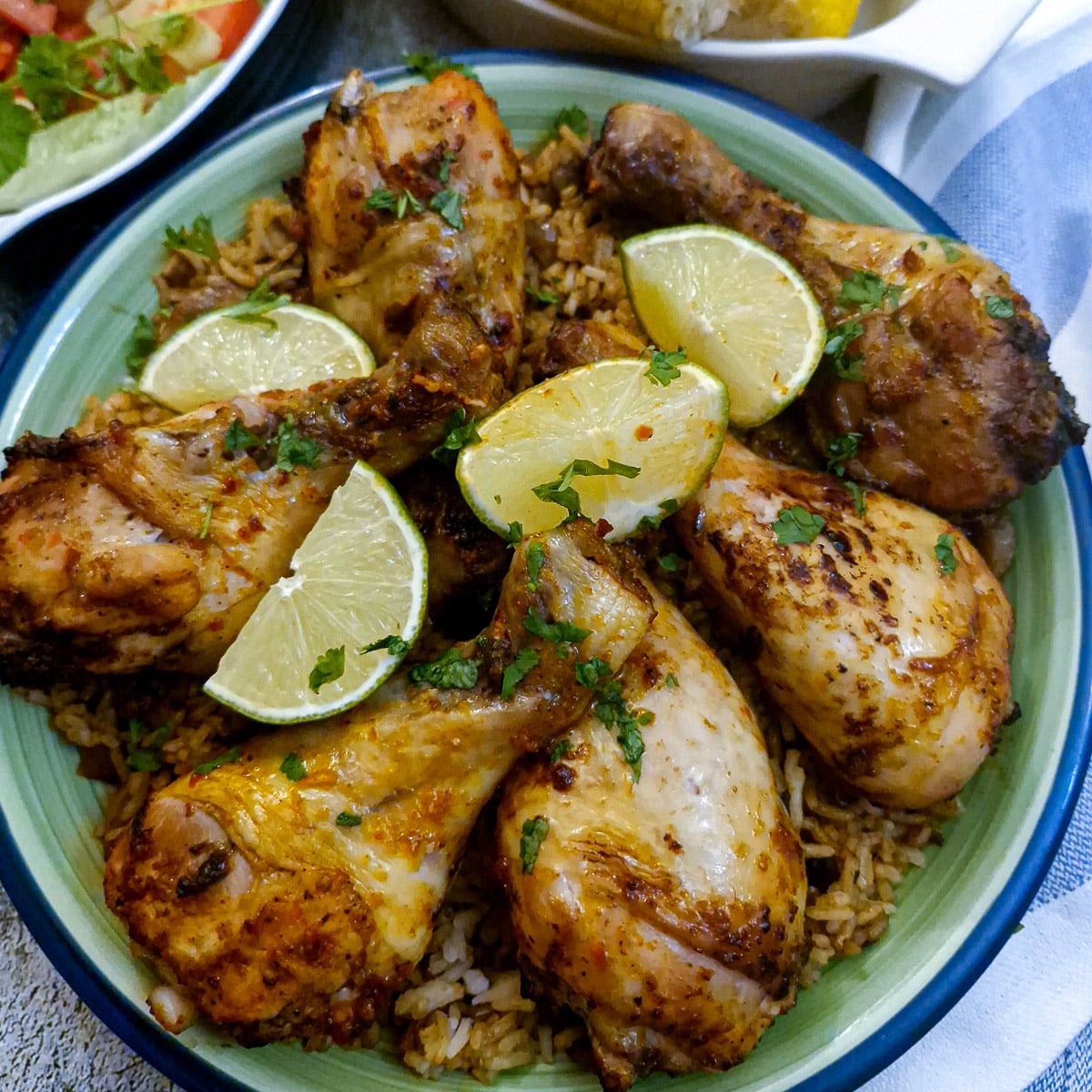 A green dish of peri peri chicken drumsticks.
