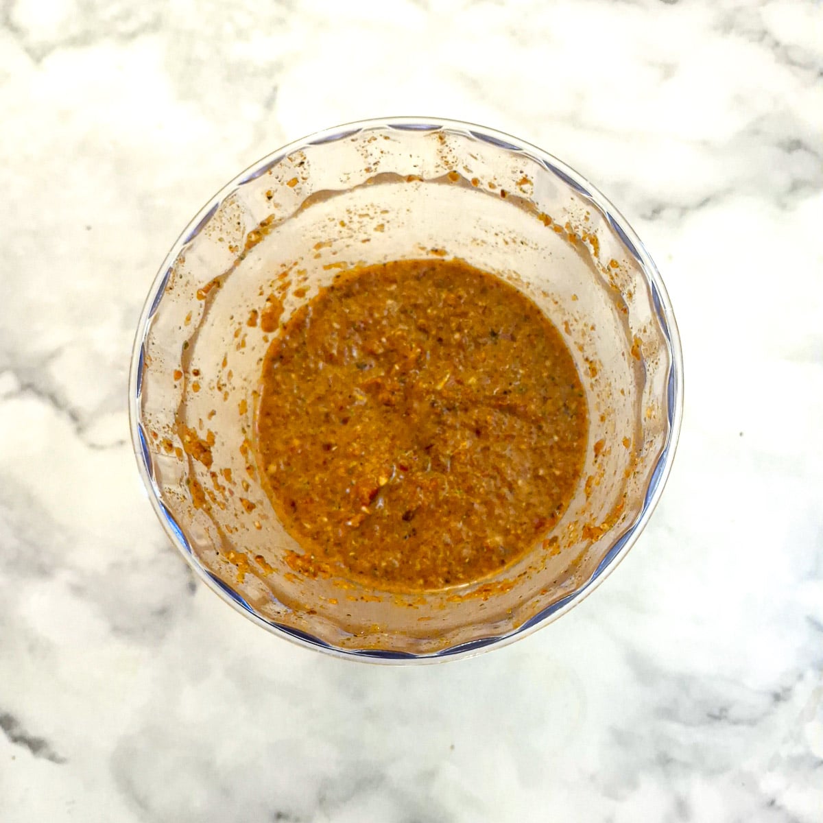 The bowl of a food processor holding blended marinade ingredients.