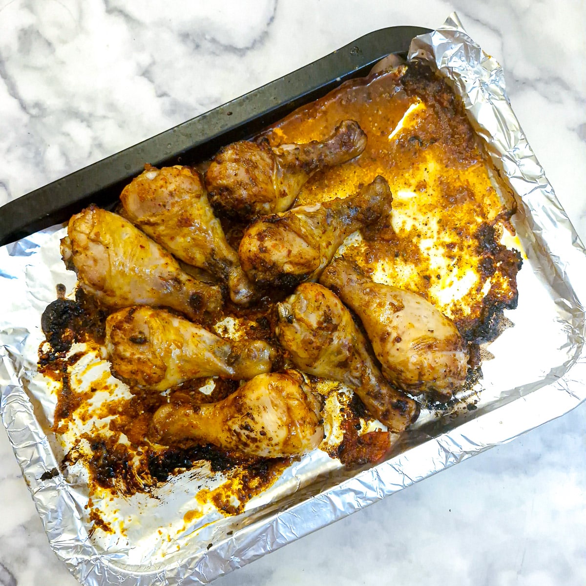 Cooked chicken drumsticks on a baking trray.