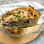 A slice of potato crust bacon and mushroom quiche being lifted from the dish on a cake lifter.