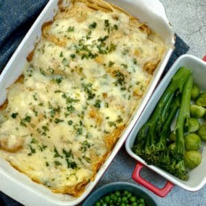 A dish of seafood-stuffed pancakes covered in cheese sauce and garnished with parsley.