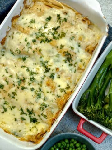A dish of seafood-stuffed pancakes covered in cheese sauce and garnished with parsley.