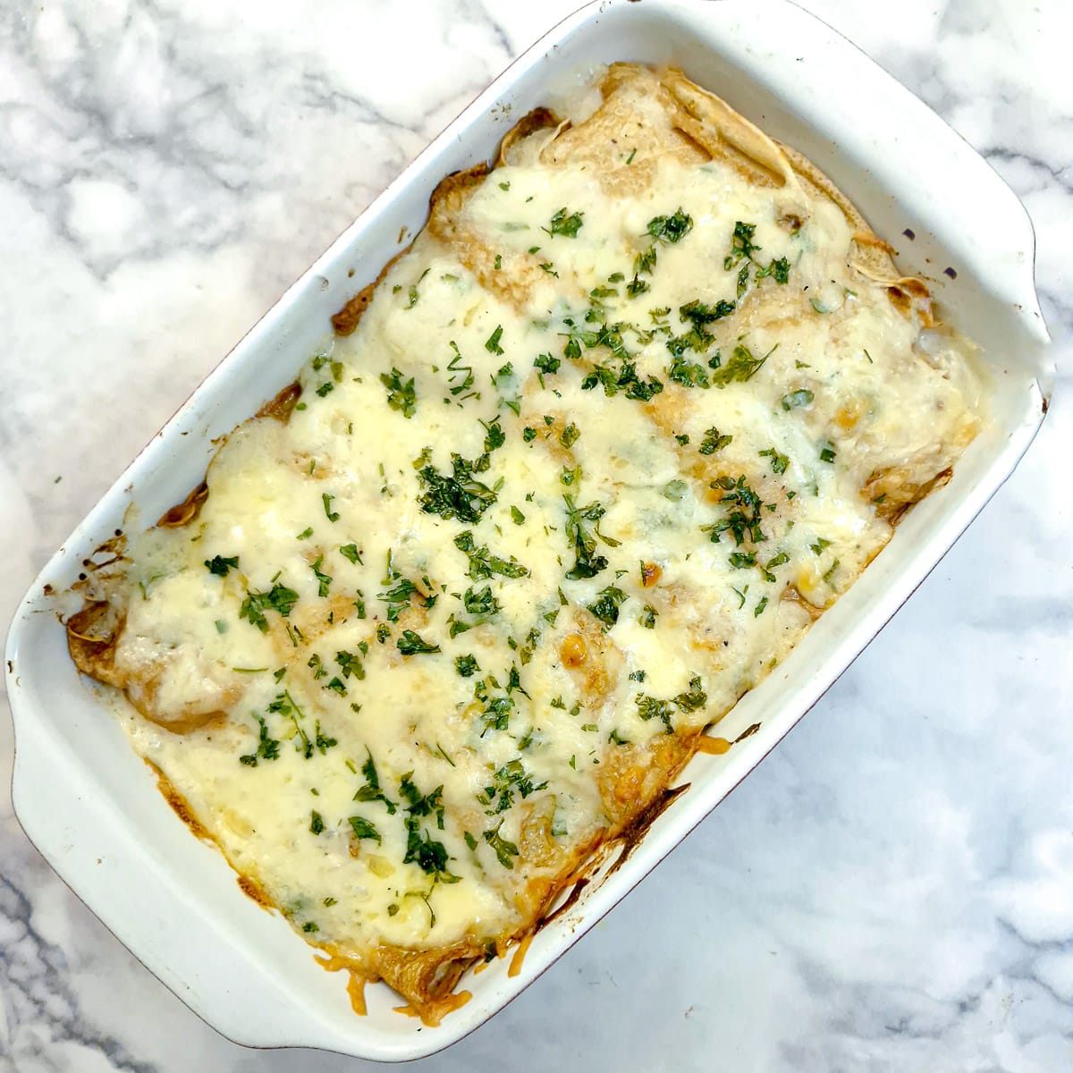 A fully baked dish of seafood stuffed pancakes covered in melted cheese.