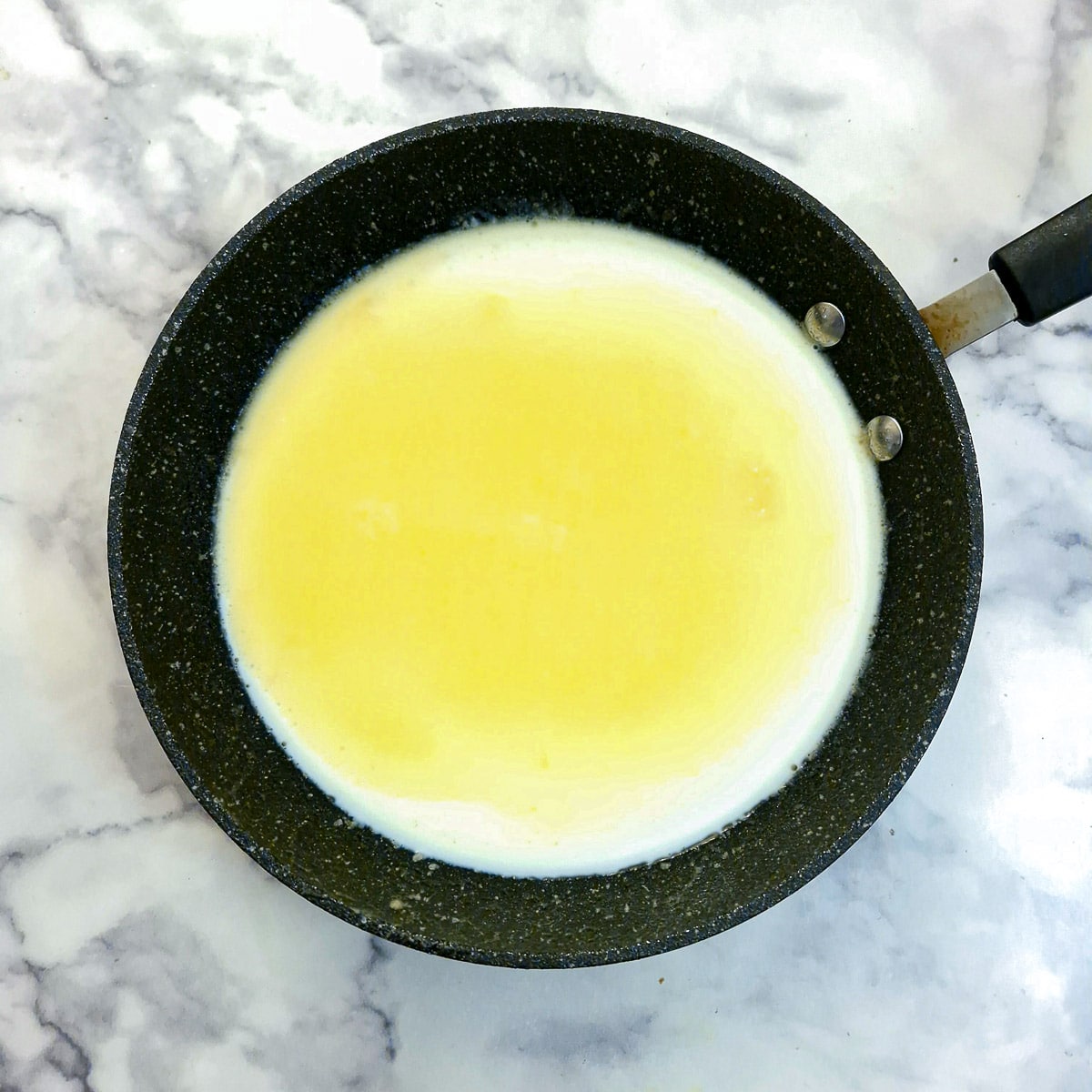 Bechamel sauce being thickened in a frying pan.