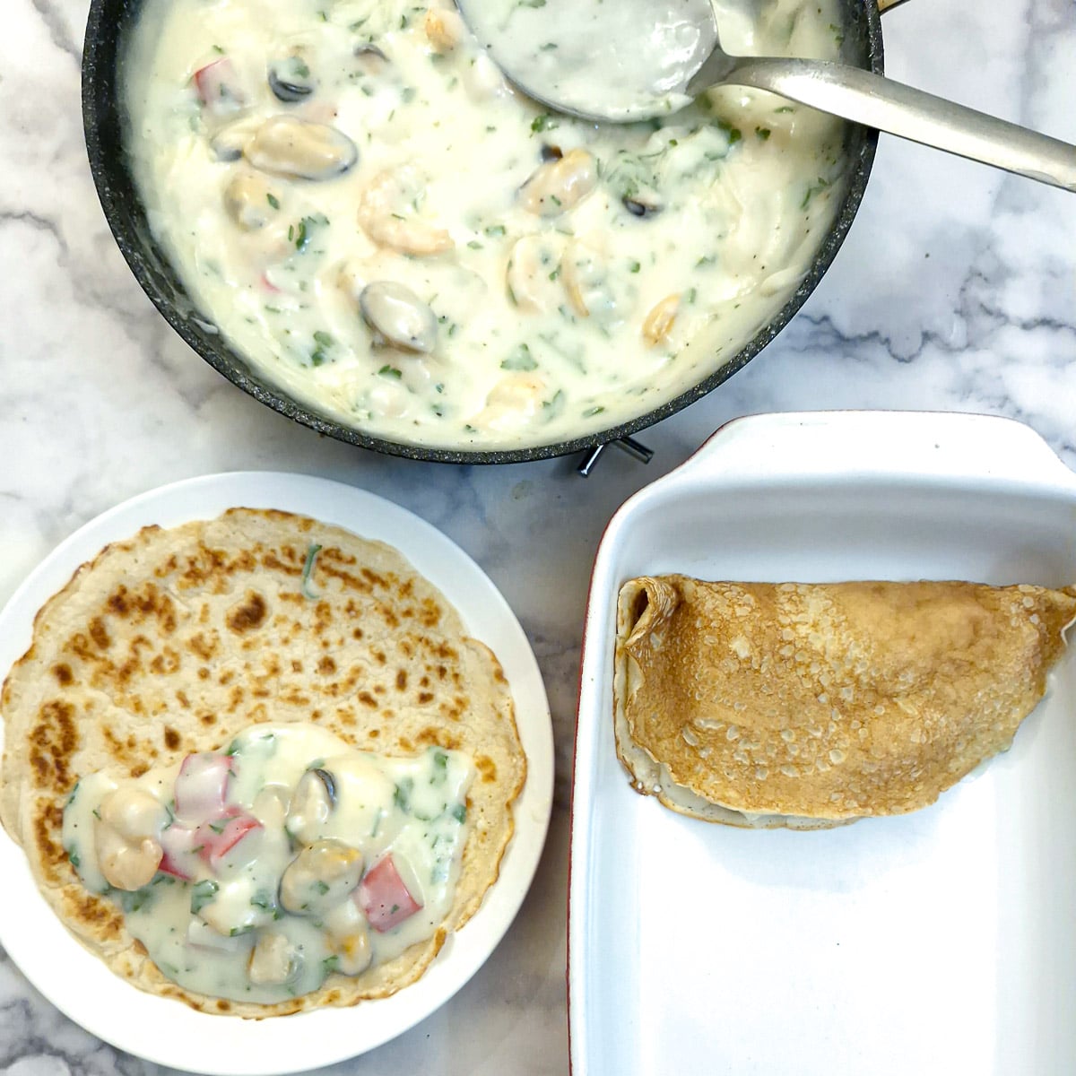 Pancakes being filled with seafood sauce and placed in a baking dish.