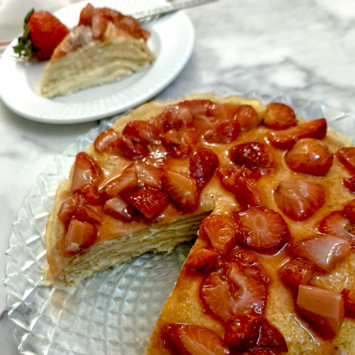 A strawberry custard pancake cake with a slice removed to a plate in the background.