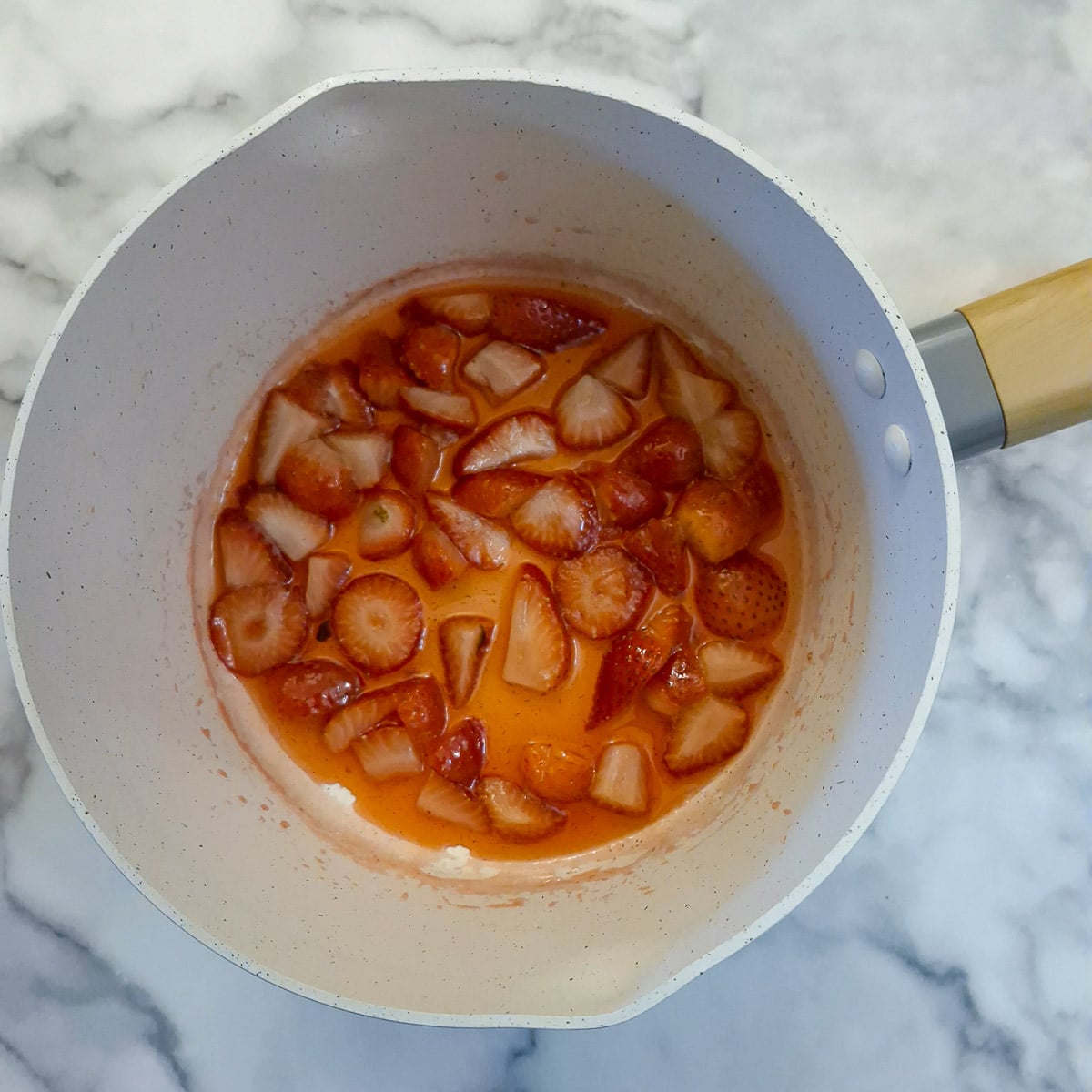 A saucepan with softened strawberries and juice.