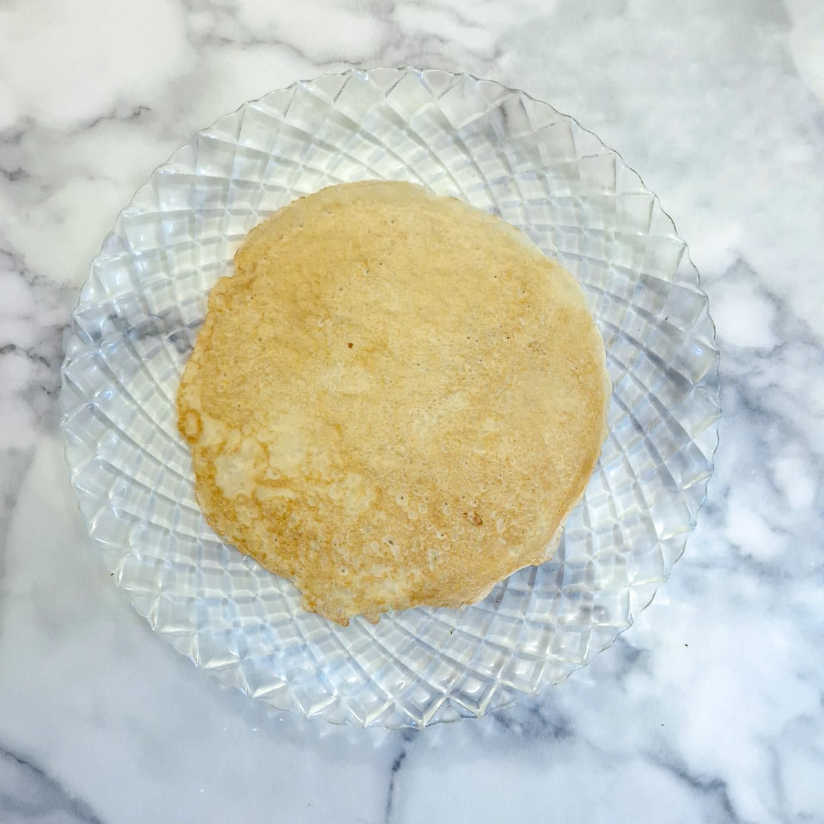 A pancake on a glass platter.