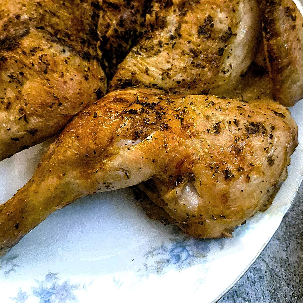 Close up of a cooked chicken leg on a plate.