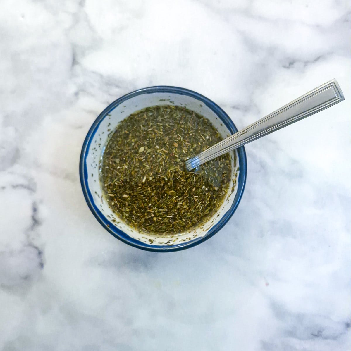 A small blue-rimmed dish of lemon and herb marinade.