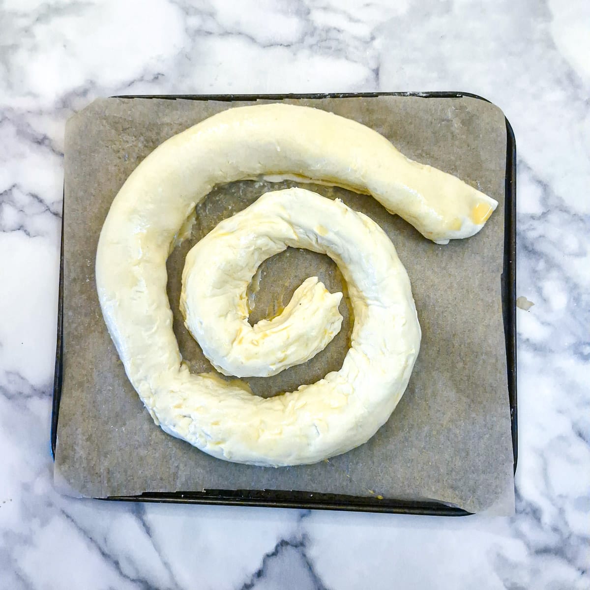 The second puff pastry and boerewors roll added to the first roll to form a larger coil.
