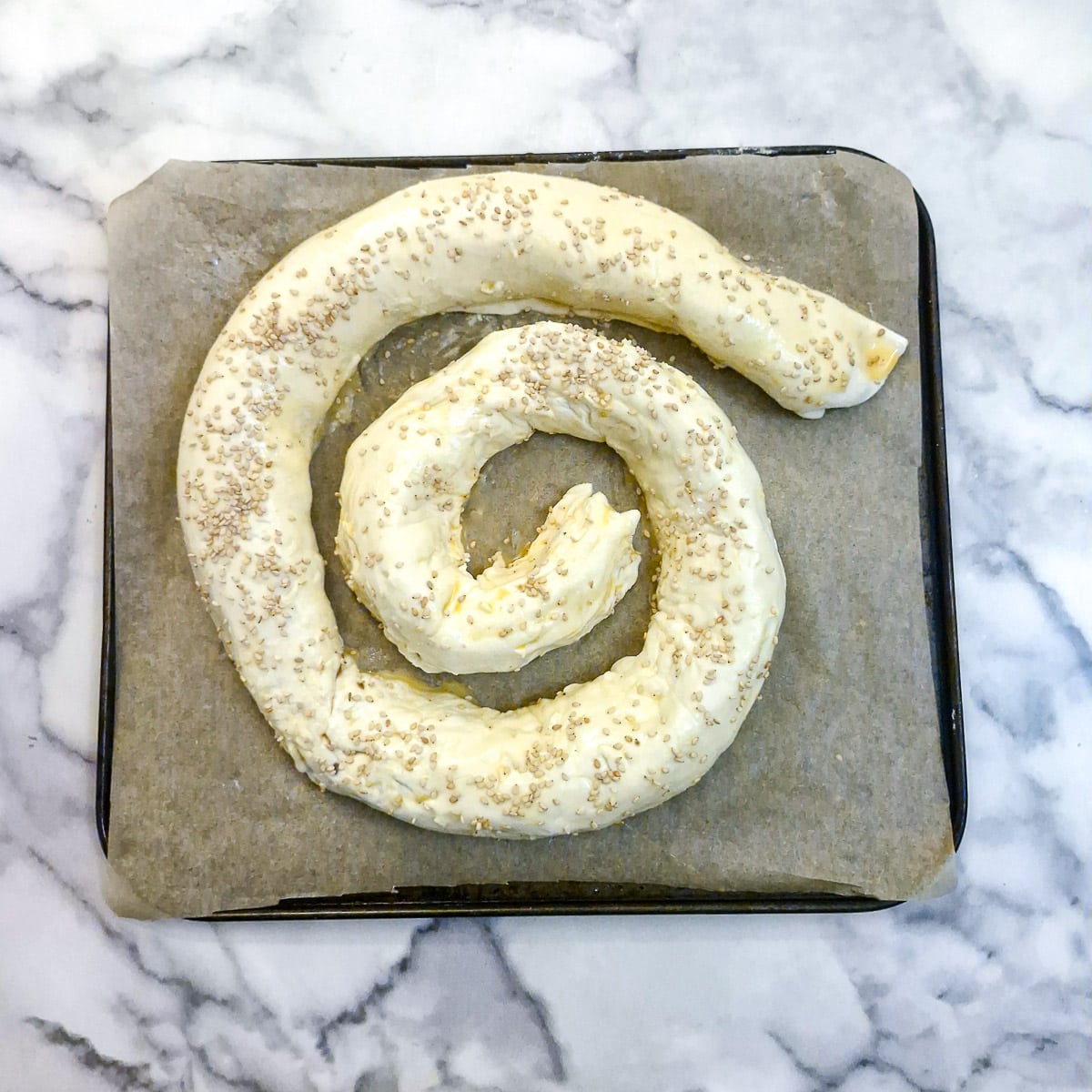 A boerewors puff pastry spiral brushed with egg wash and garnished with sesame seeds.