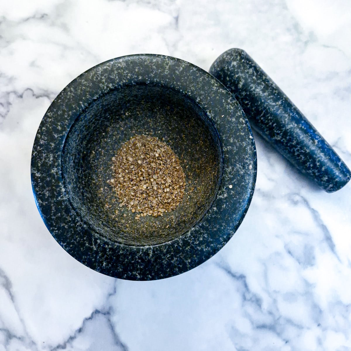 Crushed coriander seeds in a mortar and pestle.
