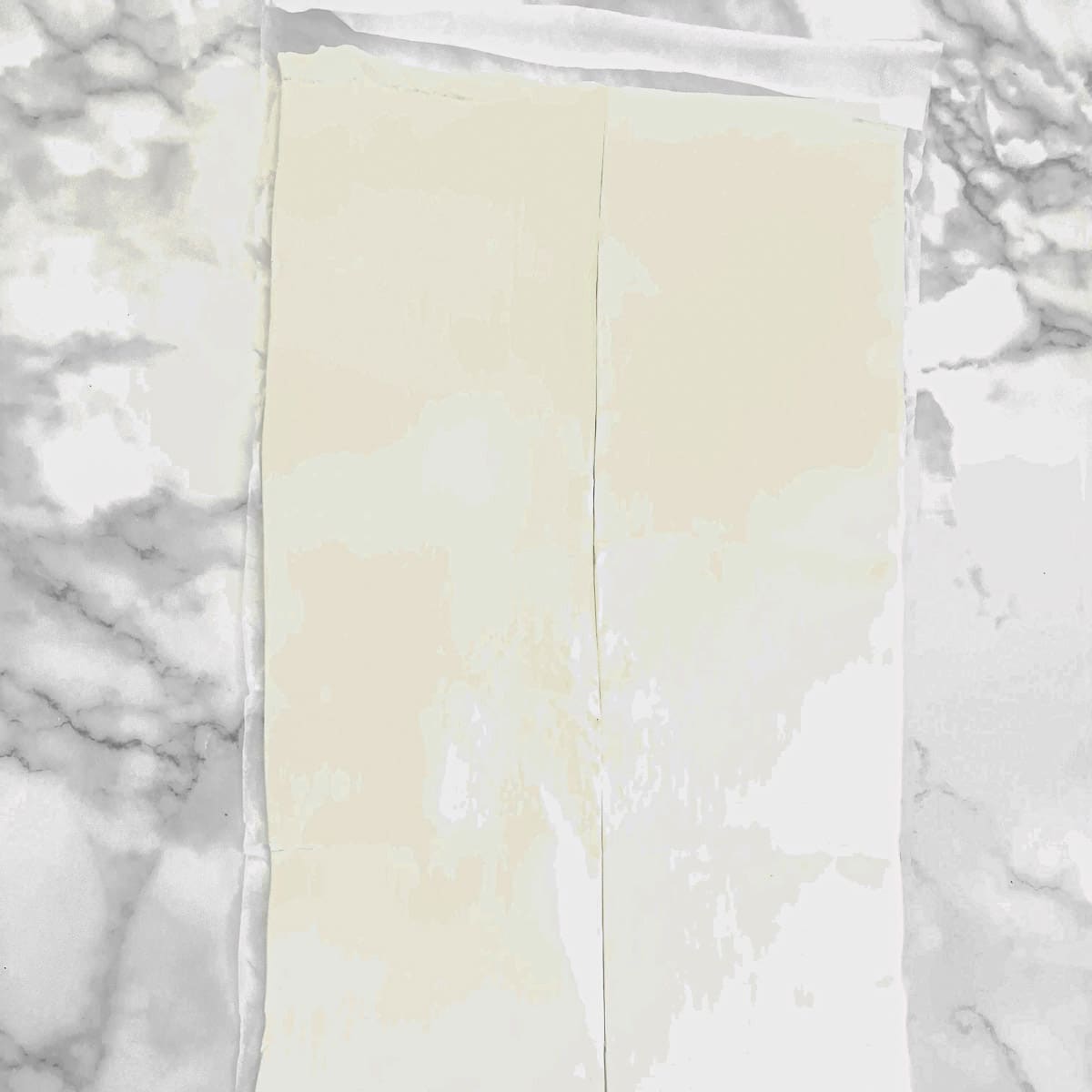 A sheet of puff pastry cut in half lengthwise.