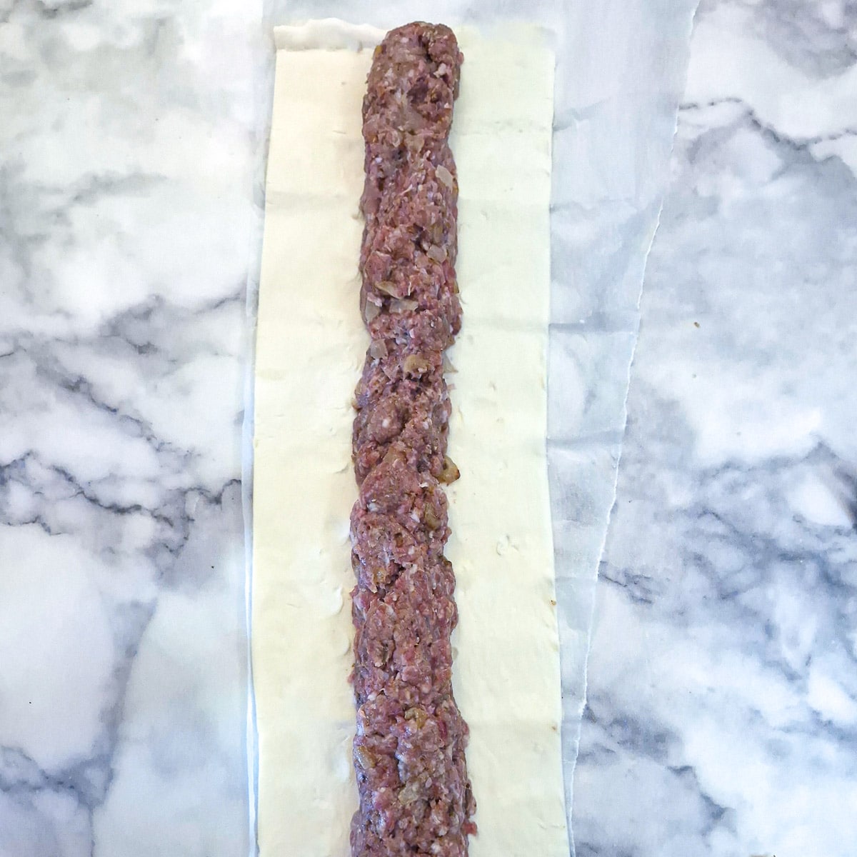 A roll of boerewors meal down the middle of a length of puff pastry.