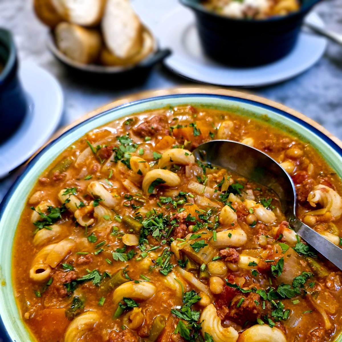 Close up of bully beef minestrone in a green serving dish.