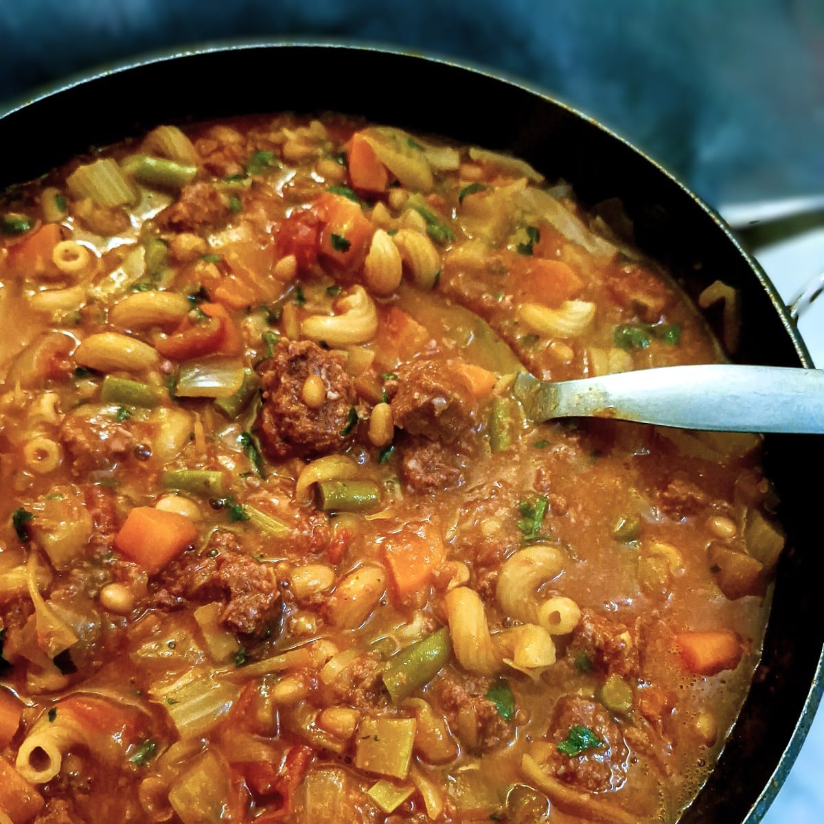 Close up of bully beef minestrone with pieces of corned beef being held in a spoon.